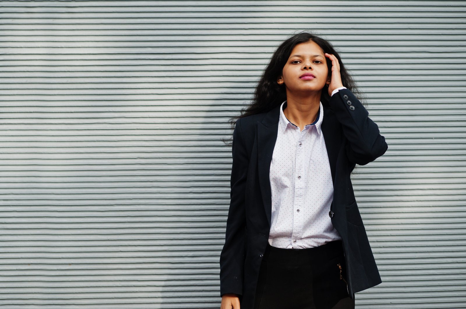 Gorgeous indian woman wear formal posing against grey wall.